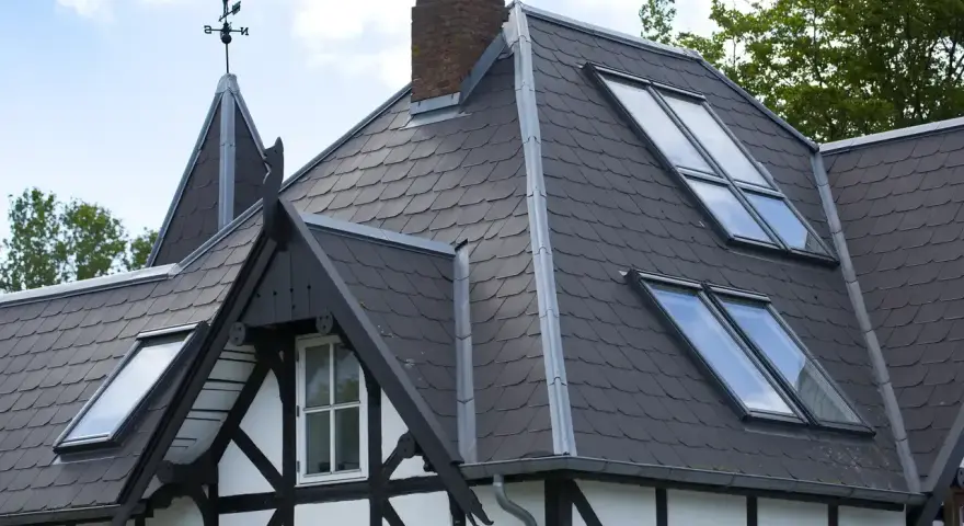 Tetti moderni con tegole scure e lucernari integrati, che valorizzano i materiali e l'architettura della casa.