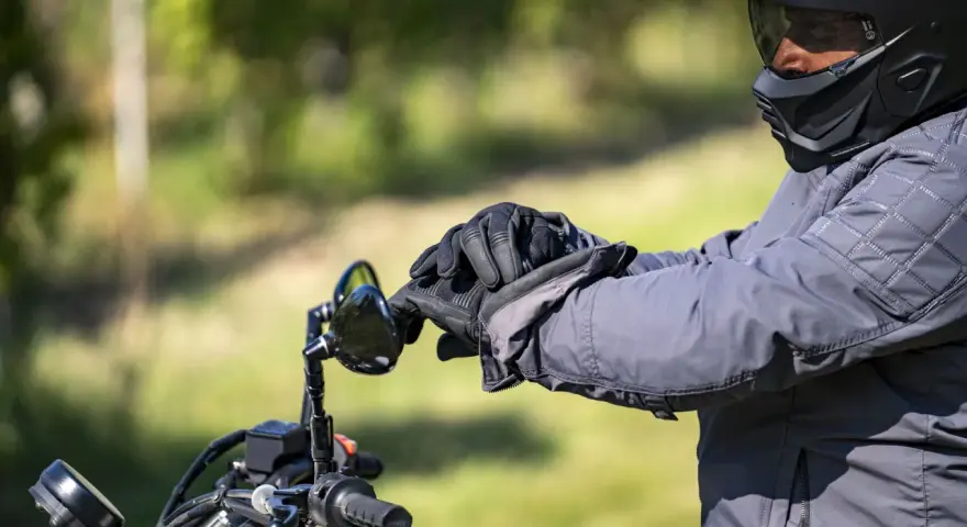 Motociclista con casco integrale obbligatorio e guanti neri, pronto per un viaggio su strada.