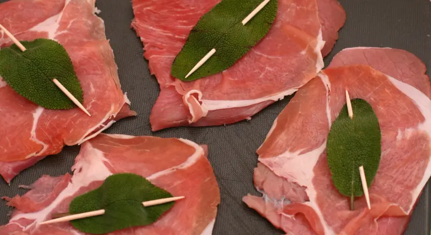 Fette di vitello pronte per la saltimbocca alla romana ricetta originale, con prosciutto crudo e foglie di salvia fissate con stuzzicadenti.