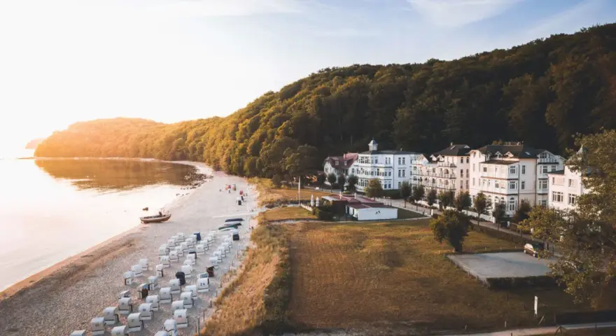 Sonnenuntergang am Binz Strand mit vielen Strandkörben, weißen Villen und einem dichten Wald.
