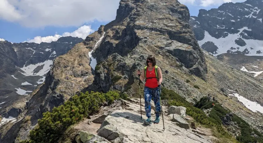 Kobieta z kijkami trekkingowymi na skalistej ścieżce w Tatrach. Czy to szlak dla każdego? Kościelec czeka!