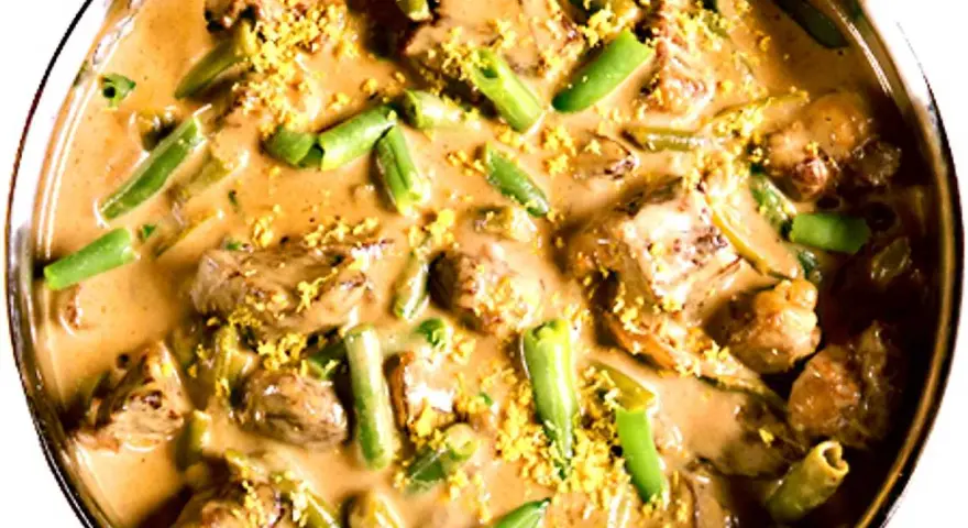 En krämig biff stroganoff med möra köttbitar och gröna bönor, toppad med gul strössel.
