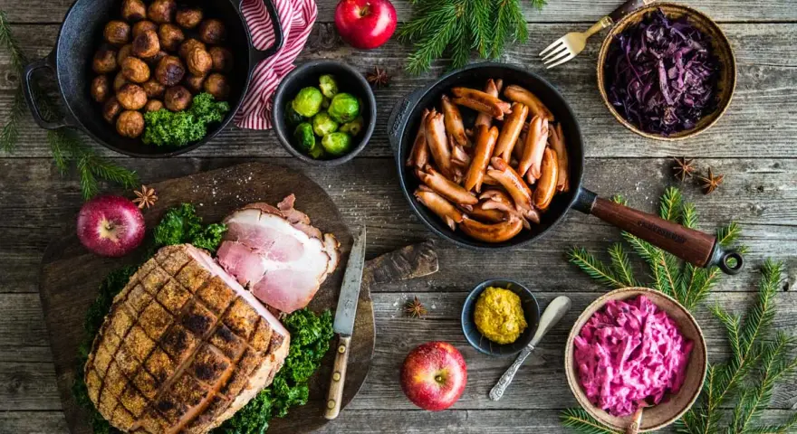 Här är en härlig bild som visar vad som finns på julbordet: köttbullar, prinskorv, julskinka, rödkål, brysselkål och äpplen.