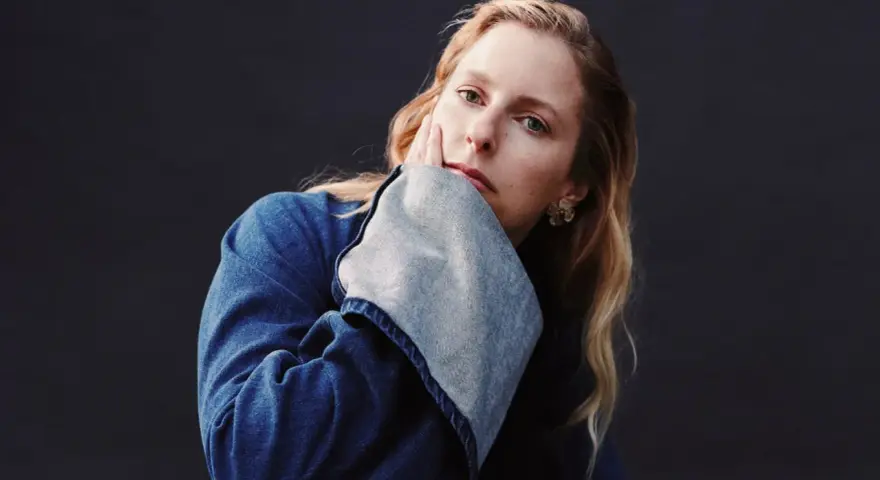 Susanne Sundfør w dżinsowej kurtce, z dłonią na policzku, jakby inspirowana utworem "Blómi".