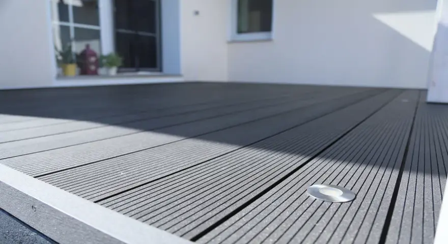 Moderne Terrasse mit grauen WPC Terrassendielen verlegen. Ein kleiner Bodenspot ist integriert.
