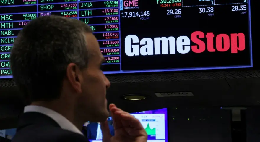 Un hombre observa la pantalla de cotizaciones de GameStop, analizando la previsión de fondos y el comportamiento del mercado.