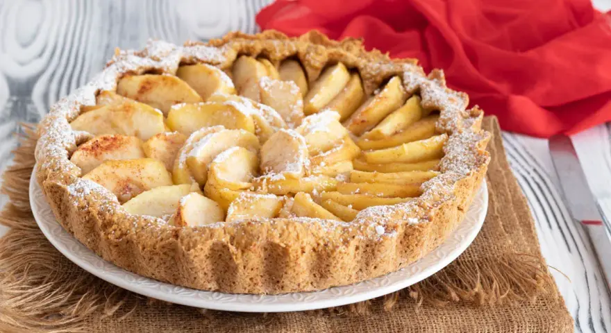 Una deliziosa crostata di mele, con mele a fette disposte a raggiera e spolverata di zucchero a velo.