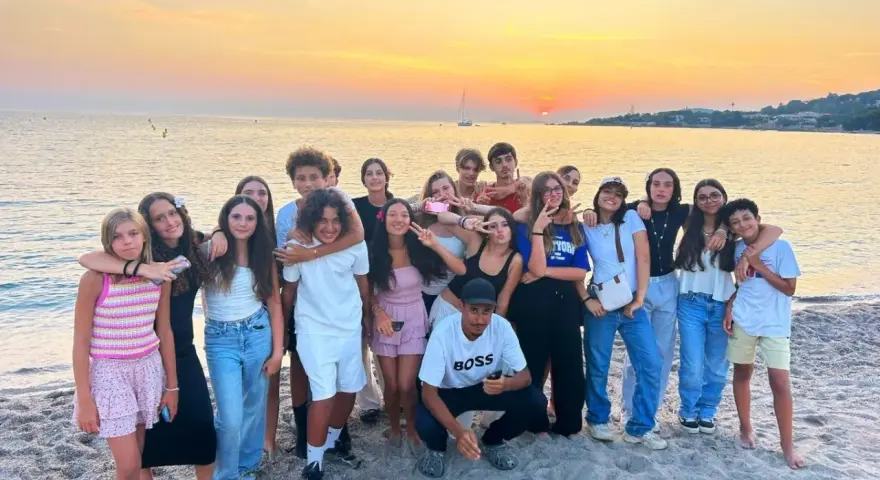 Groupe d'adolescents souriants sur une plage corse au coucher du soleil.