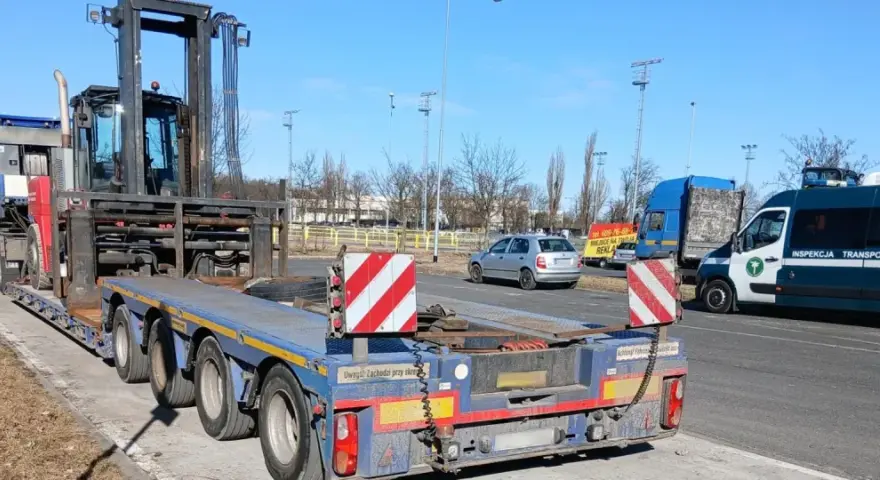 Ciężarówka z naczepą przewozi wózek widłowy. To przykład pojazdu nienormatywnego, który wymaga specjalnych zezwoleń.