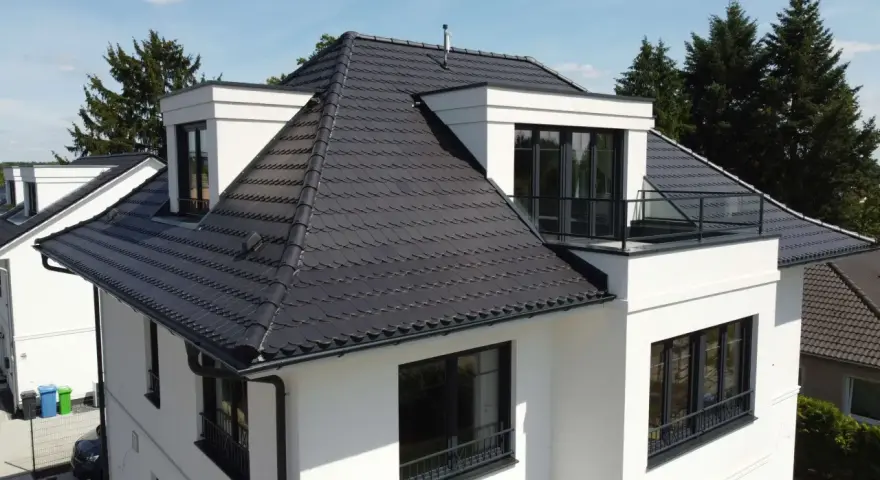 Modernes Haus mit dunkler Dachbeschichtung. Mögliche Nachteile der Dachbeschichtung: Hitzestau im Sommer, höhere Kosten bei Reparaturen.