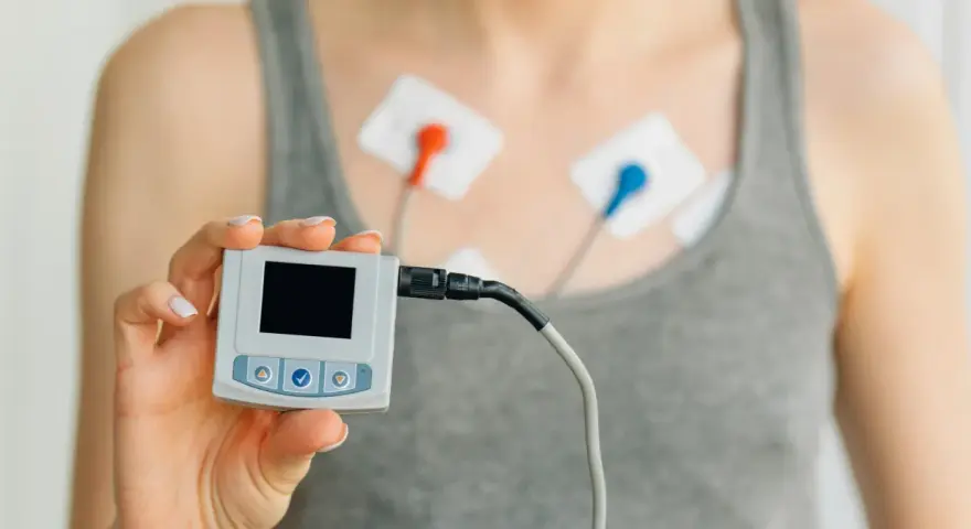 Holter co to? Urządzenie do monitorowania pracy serca z elektrodami na klatce piersiowej i małym rejestratorem w dłoni.