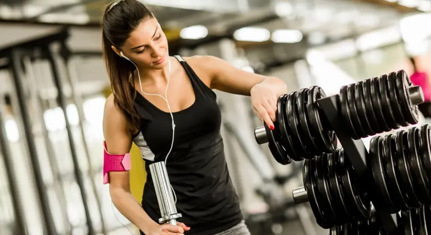 Kvinna väljer vikter på gymmet, bra gym tips för din träning.