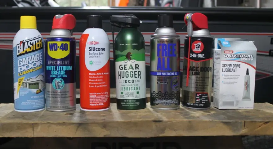 A collection of garage door lube and other lubricants, including Blaster, WD-40, Dupont Silicone, Gear Hugger, Free All, 3-in-One, and Genie Screw Drive Lubricant.