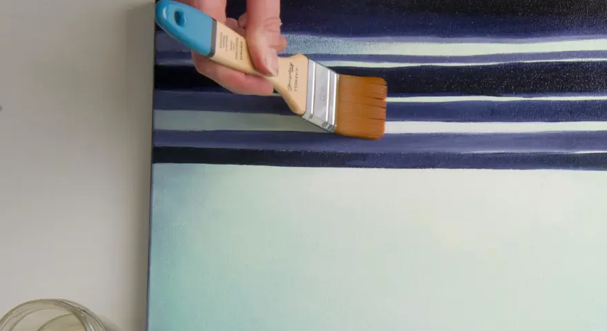 Main d'artiste appliquant une couche de vernis sur une toile aux rayures bleues et blanches. Quel vernis !