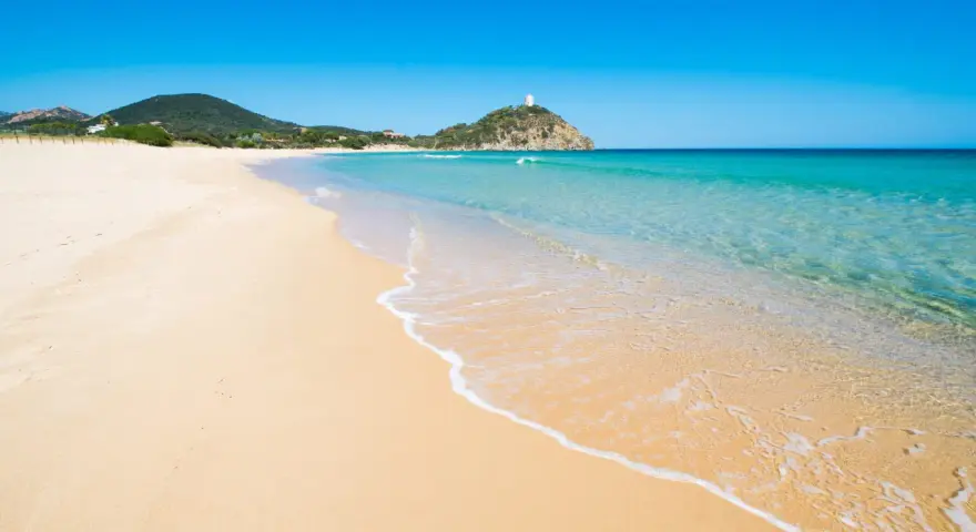 Piękne plaże Cagliari z turkusową wodą i piaszczystym brzegiem. W oddali widać wzgórze z wieżą.