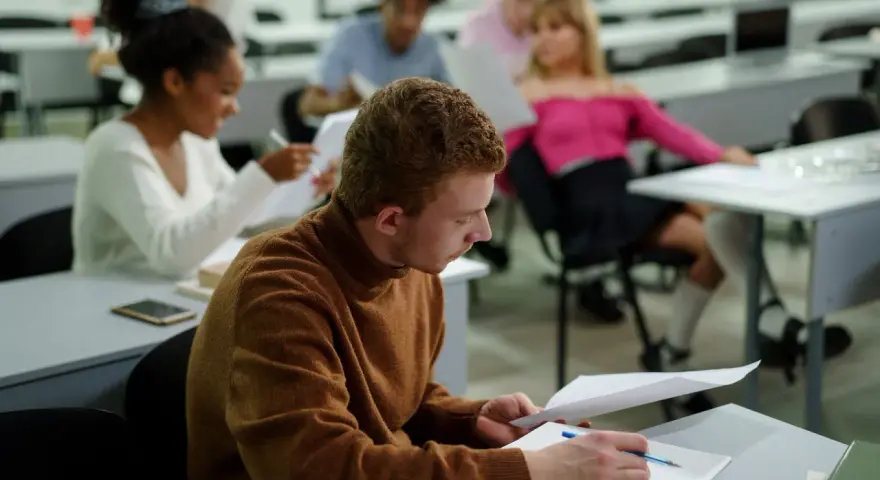 Studenci w sali wykładowej, skupieni na nauce. To dowód, że studia bez matury są możliwe i otwierają drzwi do wiedzy.
