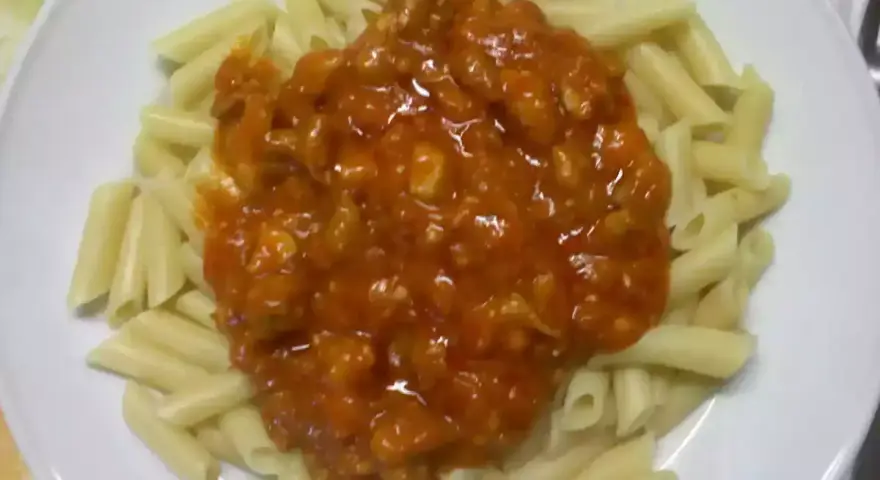 Macarrones con pollo en salsa roja, un plato casero listo para disfrutar.
