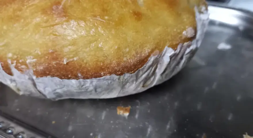 Goldbrauner Teig klebt am Backpapier, das auf einem Metallblech liegt. Ein Teil des Teigs ist bereits abgelöst.