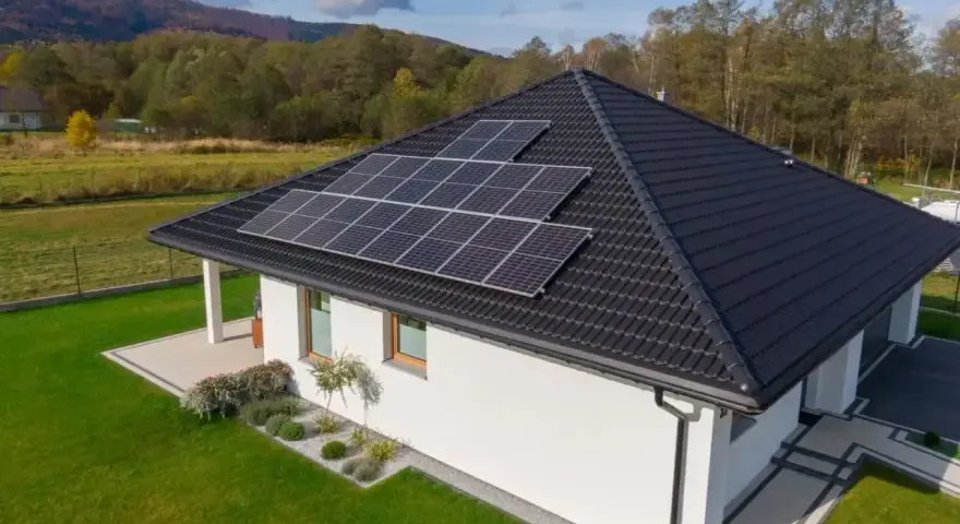 Nowoczesny dom jednorodzinny z panelami słonecznymi na dachu. Obniżone miesięczne zużycie prądu dzięki odnawialnym źródłom energii.