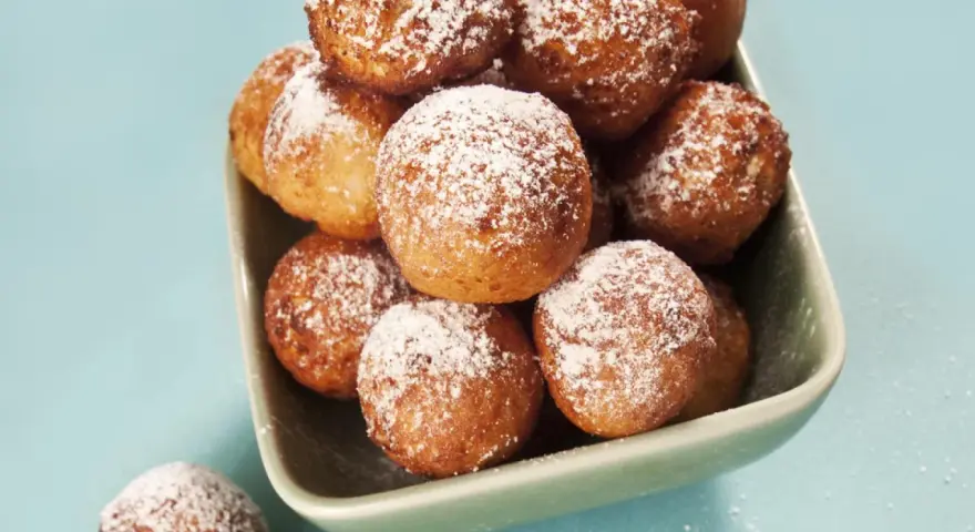 Ein Schüsselchen voller goldbrauner Mutzen, bestäubt mit Puderzucker. Ein köstliches original Mutzen Rezept zum Nachbacken.