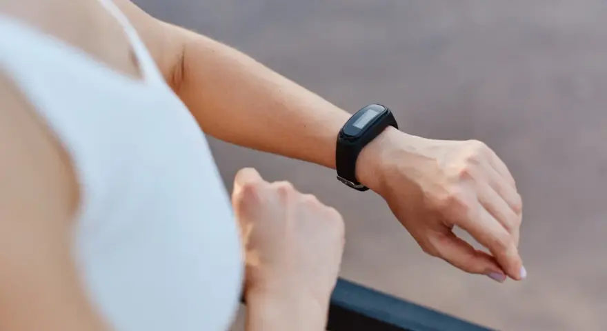 Kobieta sprawdza na swoim nadgarstku, co to jest smartband, monitorując aktywność fizyczną.