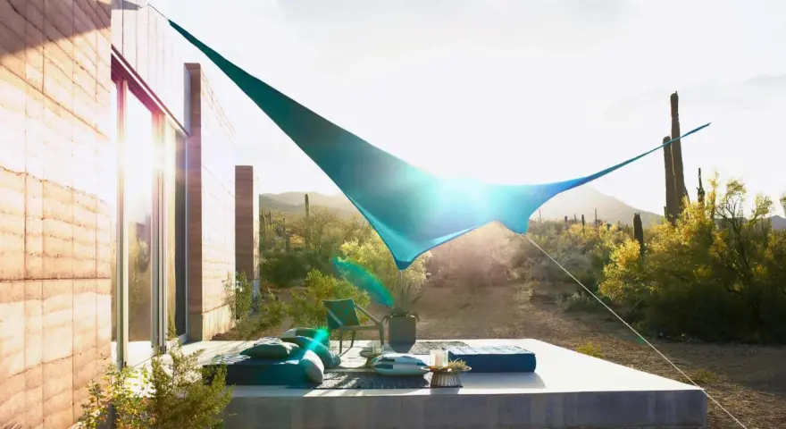 Terraza moderna con toldos vegetales que protegen del sol del desierto. Muebles cómodos y cactus al fondo.