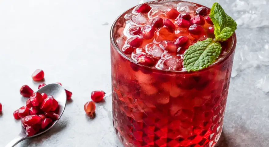 Orzeźwiający drink z grenadyną i rumem, ozdobiony świeżymi pestkami granatu i miętą. Idealny na letnie wieczory.
