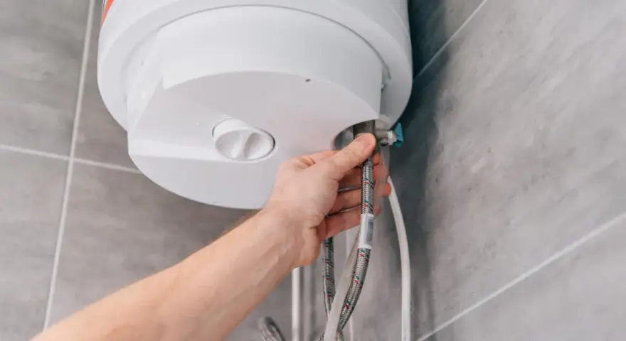 Mano che controlla i tubi di un scaldabagno a batteria non si accende.