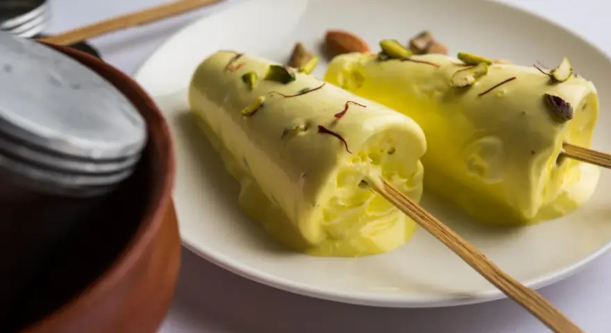 Dwa pyszne kulfi na patyku, posypane pistacjami i szafranem. Idealne na upalne dni, gdy szukasz prostego kulfi przepis.