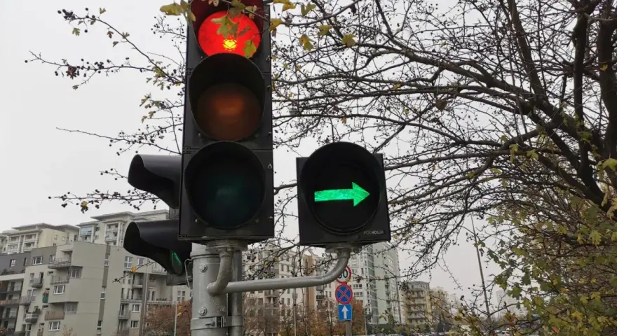 Sygnalizacja świetlna: czerwone światło na głównym słupku, a obok zielona strzałka warunkowa w prawo.