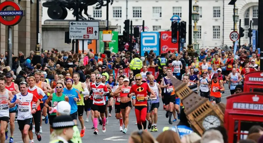 Corredores participan en el maratón de Londres, con Big Ben y cabinas telefónicas rojas de fondo.