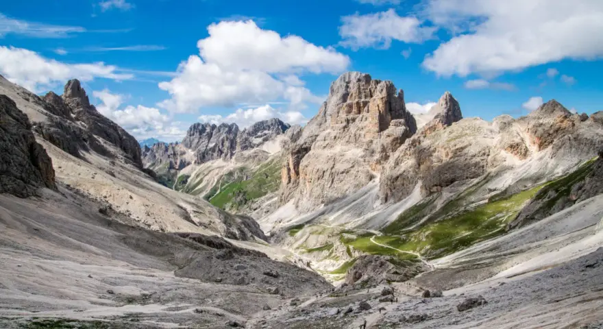 Malownicze **Val di Fassa** w Dolomitach. Kręta ścieżka prowadzi przez skaliste zbocza i zielone hale ku majestatycznym szczytom.