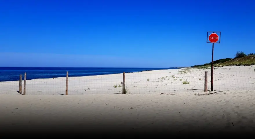 Plaża na mierzei wiślanej. Siatka i znak STOP wyznaczają granicę.