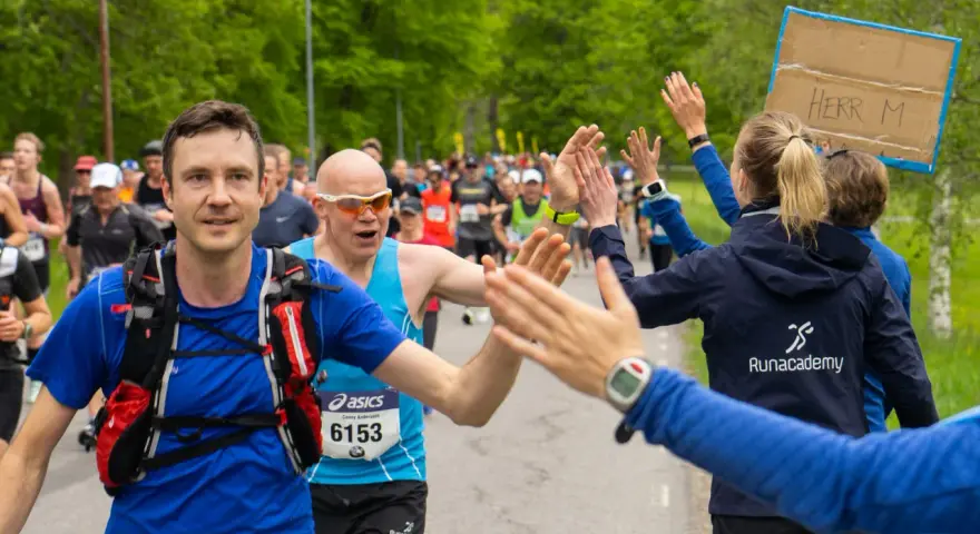 Glada löpare ger high-fives under loppet. Sista veckan innan halvmarathon, peppas deltagarna av publiken.
