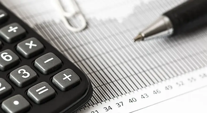 Calculadora y bolígrafo sobre gráficos. El modelo 309 para que sirve se puede deducir de estos elementos de contabilidad.
