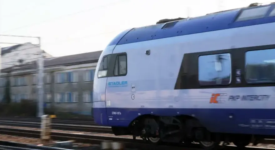Pociąg PKP Intercity Stadler ED160-007 mija budynek. Może to być widok podczas przebukowania biletu na podróż.