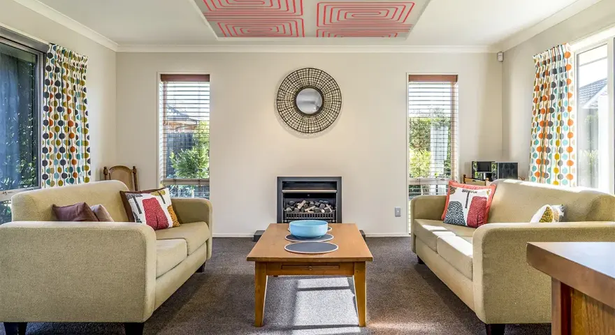 Sala de estar con sofás, chimenea y un moderno techo radiante con patrón de espiral roja.