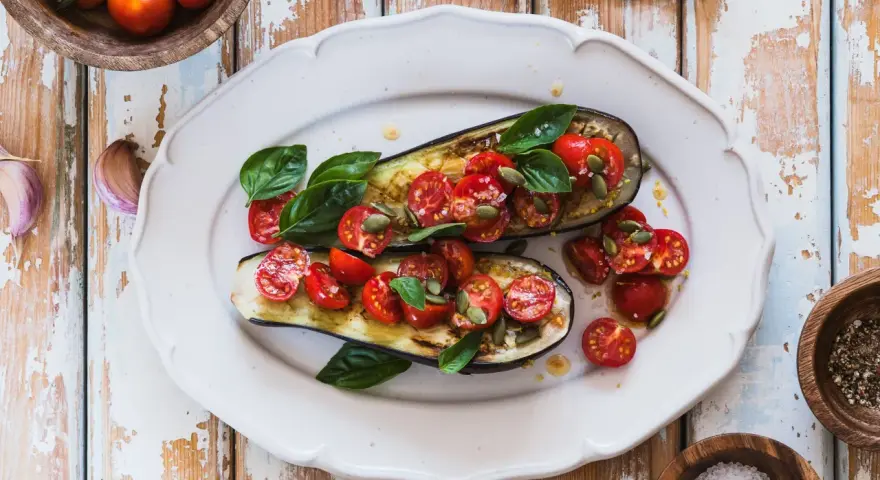 Melanzane ripiene vegetariane con pomodorini, basilico e semi di zucca, un piatto colorato e saporito.