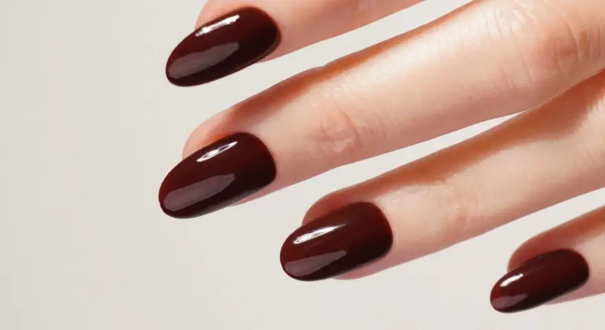 Une idée manucure automne : des ongles courts et arrondis, vernis d'un brun chocolat profond et brillant, évoquant la douceur des feuilles mortes.