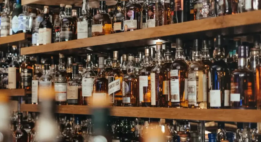 Regale voller Flaschen mit bernsteinfarbenem Whisky oder Whiskey. Eine große Auswahl für Kenner.