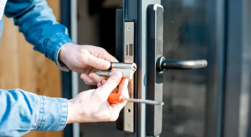 Mani che sostituiscono serratura porta con cacciavite.