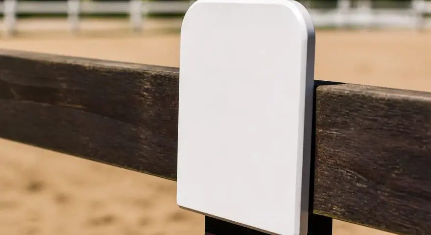 Un panneau blanc vierge sur une clôture en bois dans une carrière de dressage.