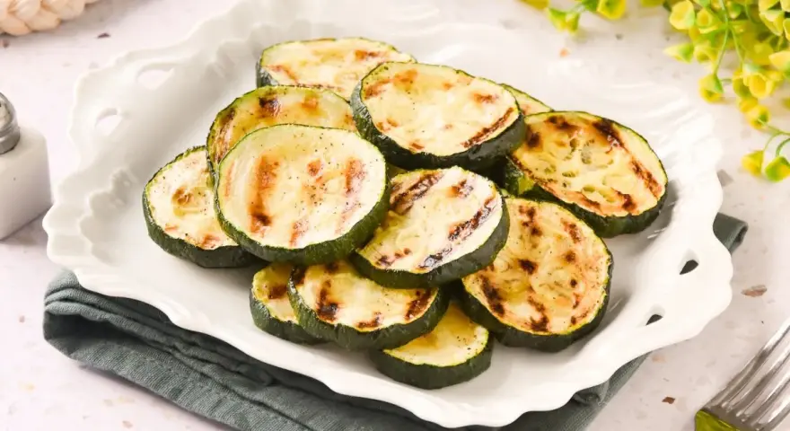 Rodajas de calabacín a la plancha, tiernas y con marcas de parrilla, servidas en un plato blanco.