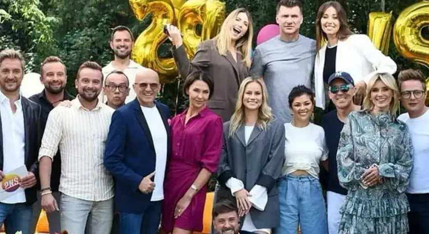 Ekipa TVP2 Pytanie na śniadanie dzisiejszy odcinek świętuje 28 lat! Radosna grupa prezenterów i gości pozuje do wspólnego zdjęcia na tle złotych balonów.