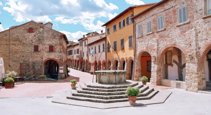 Piazza con pozzo antico e case in pietra e intonaco colorato, un assaggio di cosa vedere a Civitella in Val di Chiana.