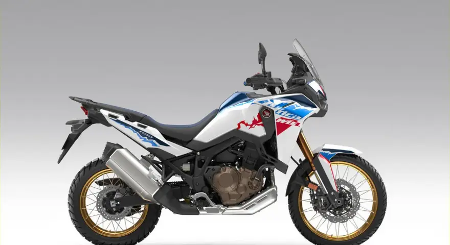 Nowy motocykl Honda Africa Twin 1100 w białym malowaniu z niebieskimi i czerwonymi akcentami, gotowy na przygodę.