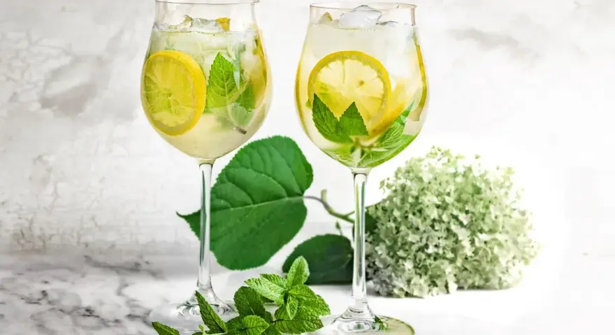 Orzeźwiający drink z prosecco i sprite, z plasterkami cytryny i listkami mięty, podany w kieliszkach. Idealny na letnie popołudnie.
