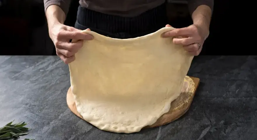 Rozciąganie elastycznego ciasta na pizzę, idealnego do szybkiego przepisu na ciasto do pizzy.