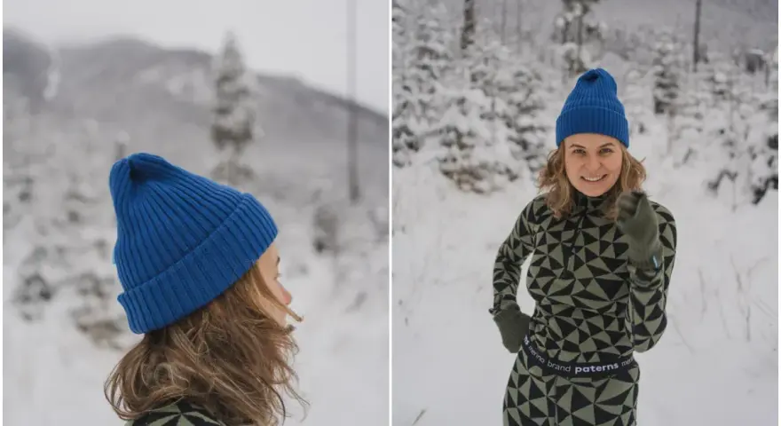 Uśmiechnięta kobieta w zimowym krajobrazie, ubrana w komplet z wełny merino. Jej strój podkreśla właściwości tej naturalnej tkaniny: ciepło i komfort.