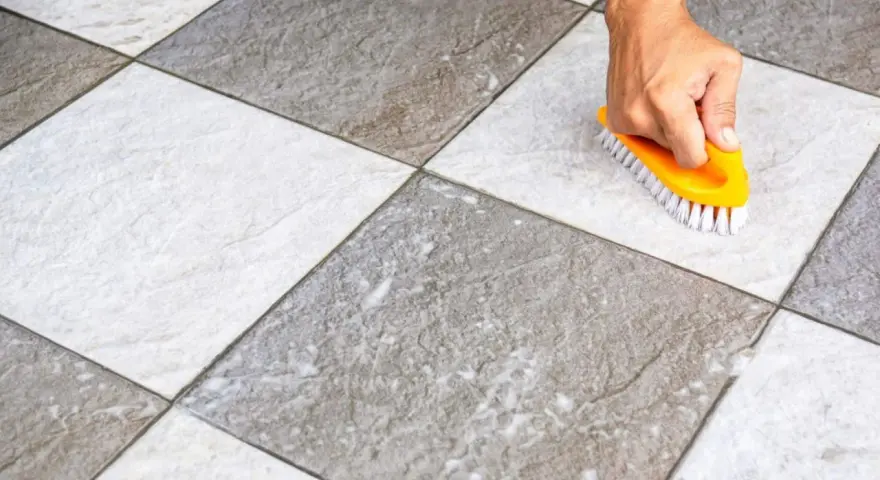 Main tenant utilise une brosse jaune pour faire briller le carrelage, révélant sa beauté naturelle.